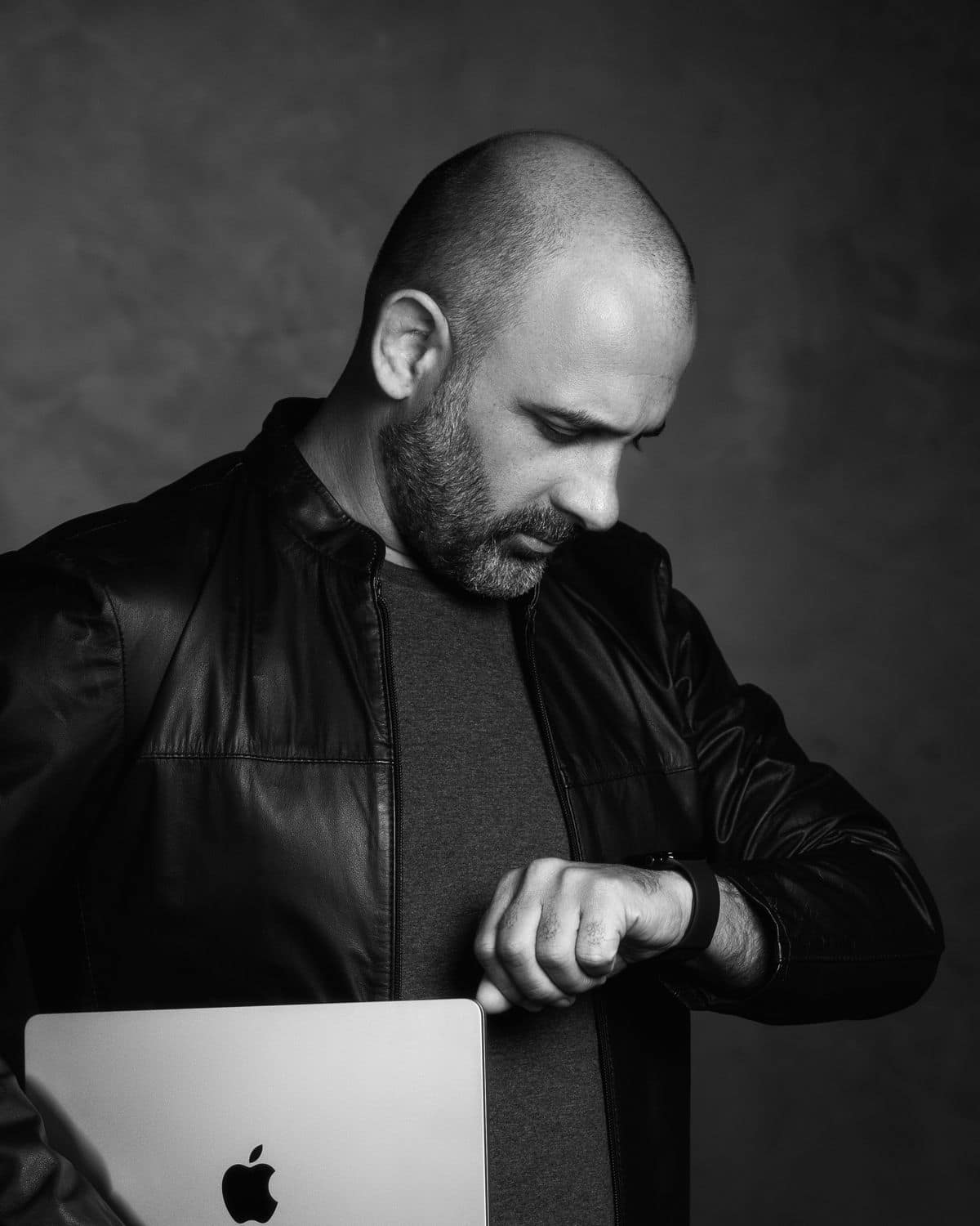 Gregori Dalzotto de pé, segurando um notebook e olhando o relógio